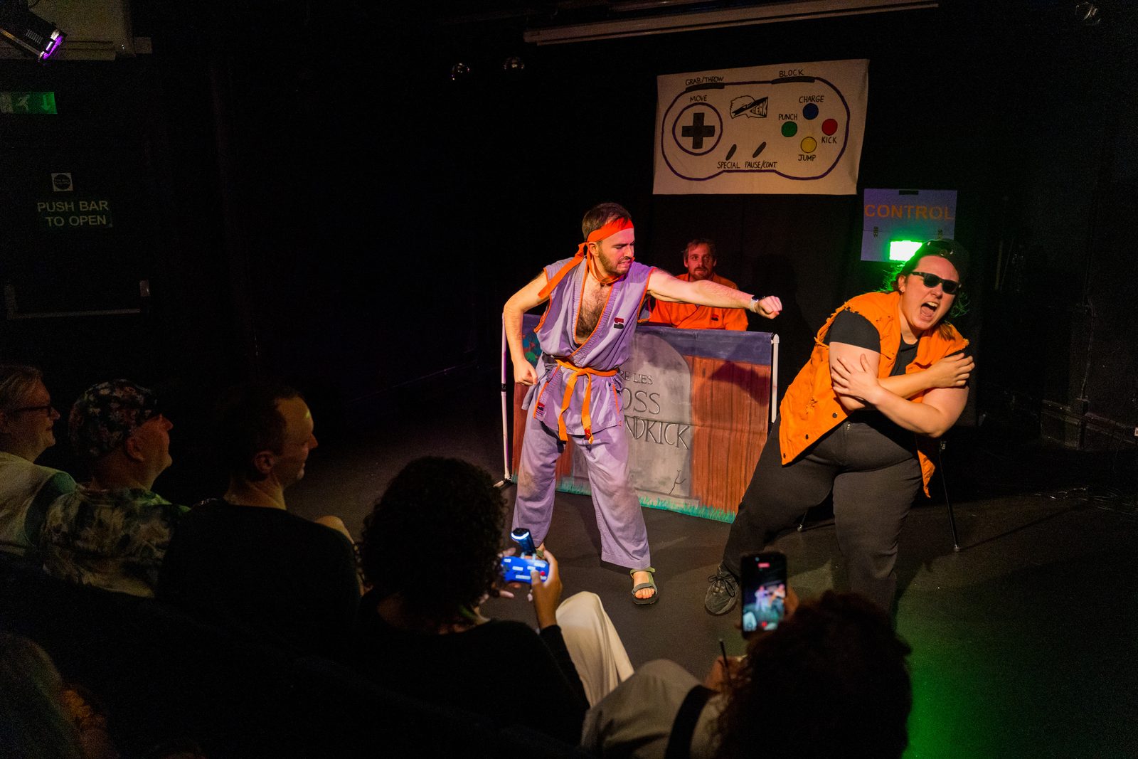 Karate Man mid-punch beside a goon, an audience member holding the controller in the foreground